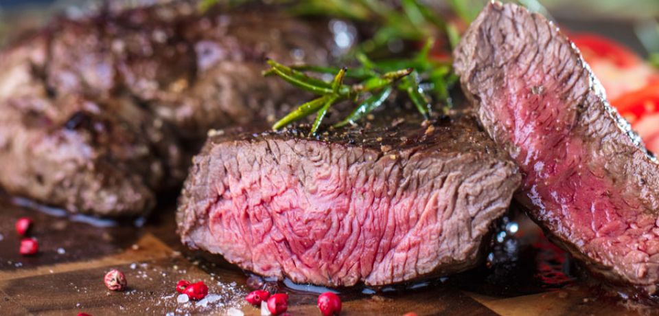 zwei saftige medium gebratene Steaks garniert mit rotem Pfeffer und Rosmarin